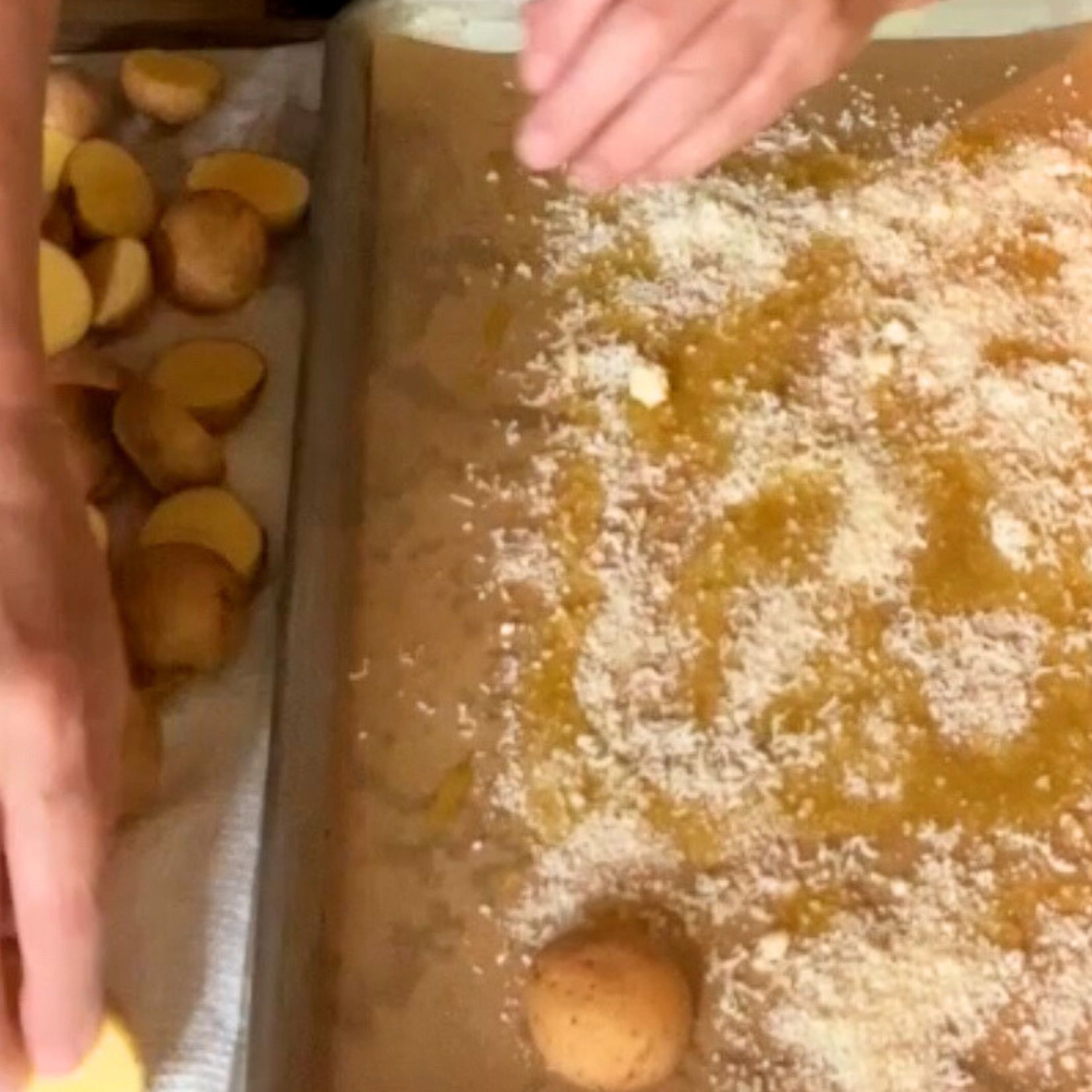 Sheet pan with parchment paper and grated Parmesan. A potato placed cut side down on the Parmesan.