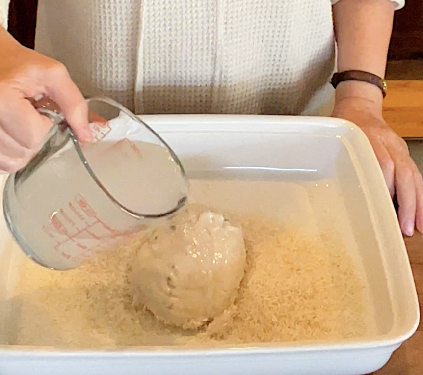 Rice, cream of chicken soup, water being put into a baking dish.