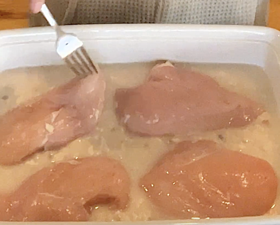 Chicken added to the rice, cream of chicken soup and water in a baking dish to make old-fashioned chicken and rice casserole.