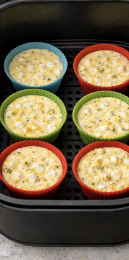 Ricotta egg bites and silicone muffin tins that are blue green and red. On a dark colored baking sheet.