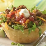 Taco Cup make with Biscuits wit toppings on a plate with a fork.