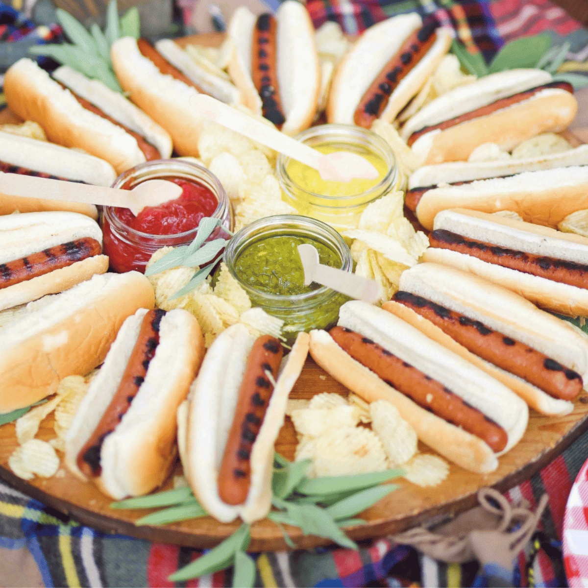 Hot dog board with grilled hot dogs, buns, potato chips, ketchup, mustard, and relish for easy tailgate food.
