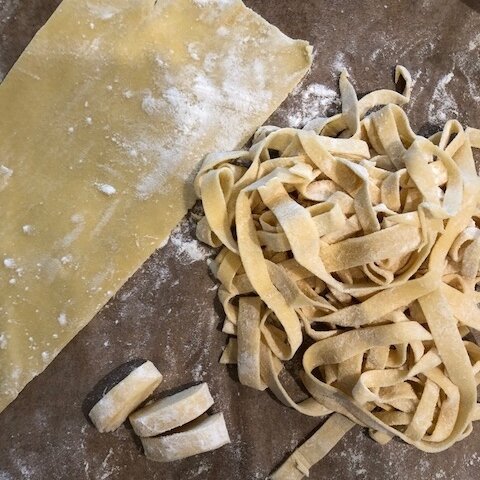 Homemade pasta tagliatelle on cutting board.