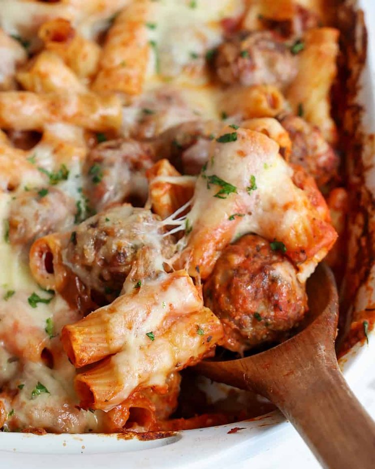 Rigatoni meatballs and melted cheese and a casserole with a wooden spoon