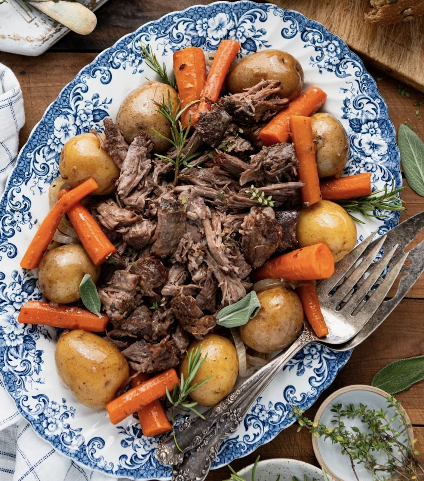 Old Fashioned Pot Roast  with carrots and potatoes on a blue and white serving platter.