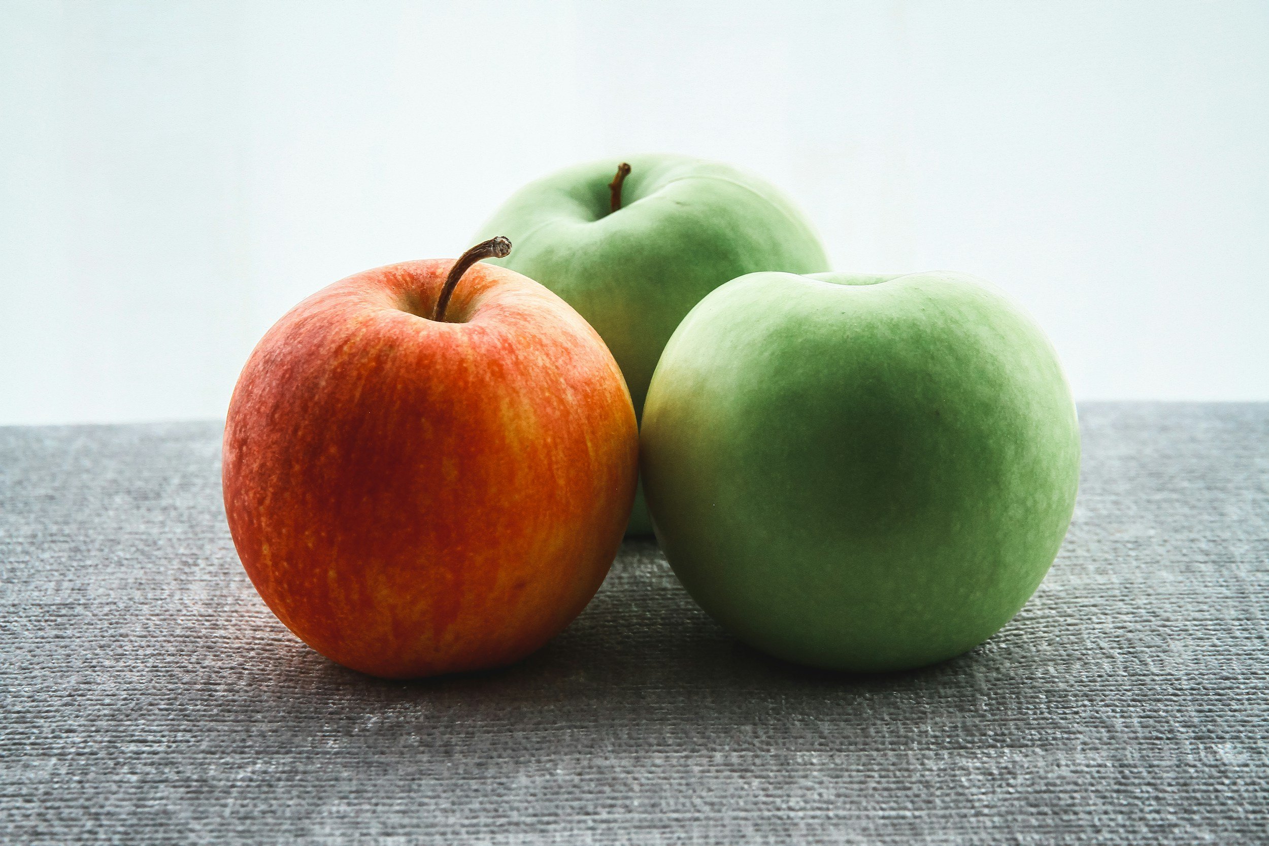 Best apples for baking, with a picture of three apples. One green one red on a piece of fabric with a light blue background.