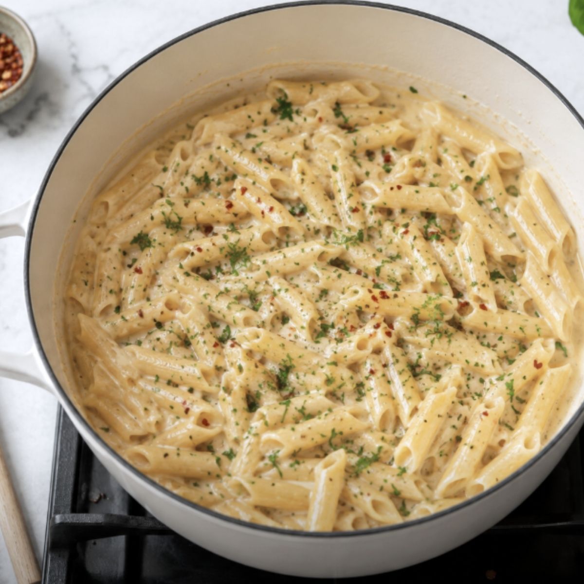 pan of pasta with cottage cheese pasta sauce with penne pasta, garnished with red pepper and herbs.