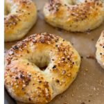 Cottage Cheese Bagels on parchment paper. Big golden brown with everything bagel seasoning on top.