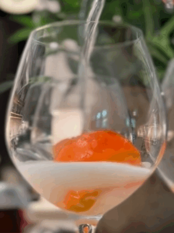 Apperal spritz ice cubes in a wine glass being filled with Prosecco.