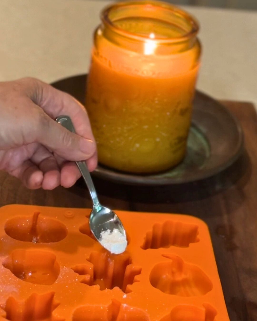 Edible glitter going into an ice cube mold with a fall vibe and a lit candle