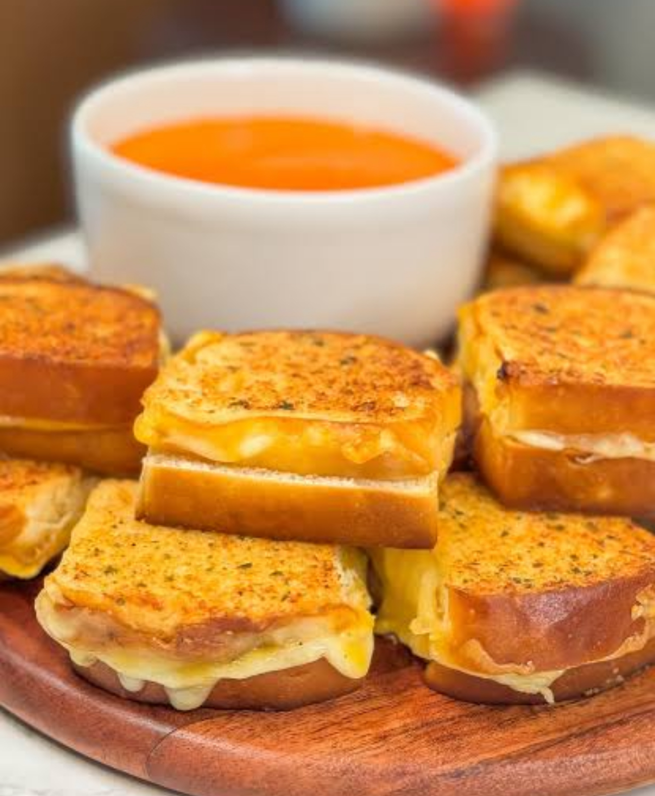 Grilled cheese sliders with tomato soup, stepped high on a white platter.