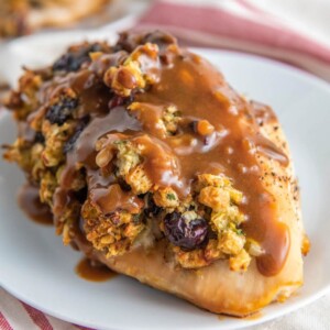 A chicken breast stuffed with stuffing on a white plate, smothered and gravy