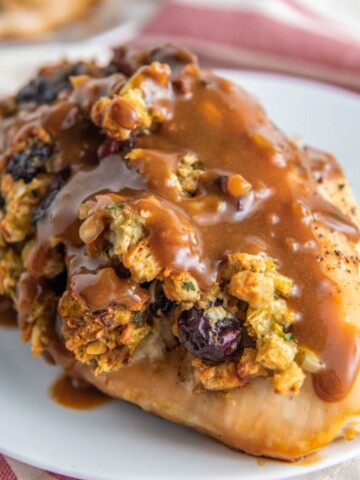 A chicken breast stuffed with stuffing on a white plate, smothered and gravy