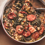 Black Eyed Peas soup, sausage and kale in a pan with a cloth with a spoon