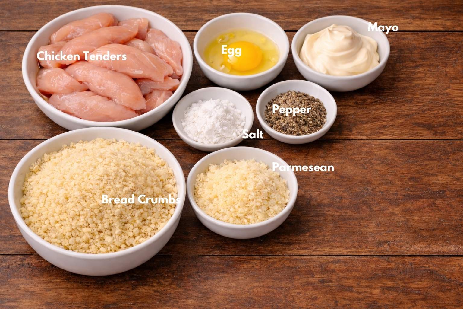 ingredients for baked chicken fingers recipe including chicken tenderloins, panko, parmesan, eggs and spices.