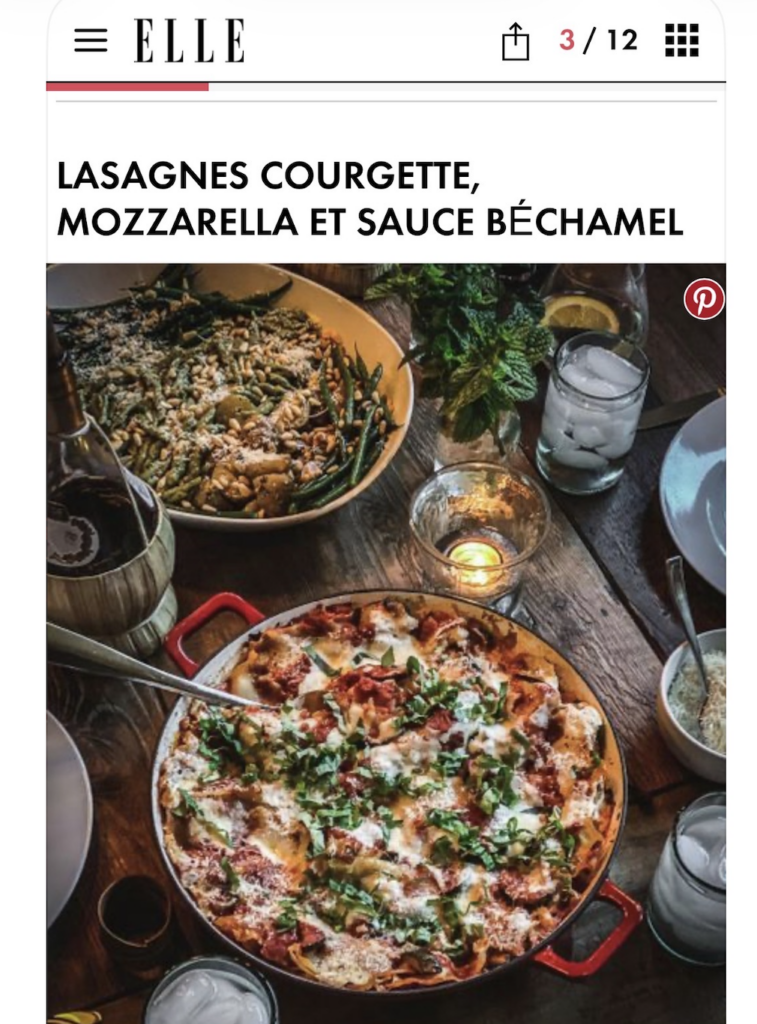 An Elle magazine spread with lasagnas on a wood table with candles and waters and wine.