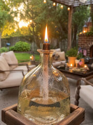 Glass bottle turned into a DIY mosquito repellent, tiki torch on a pretty patio.