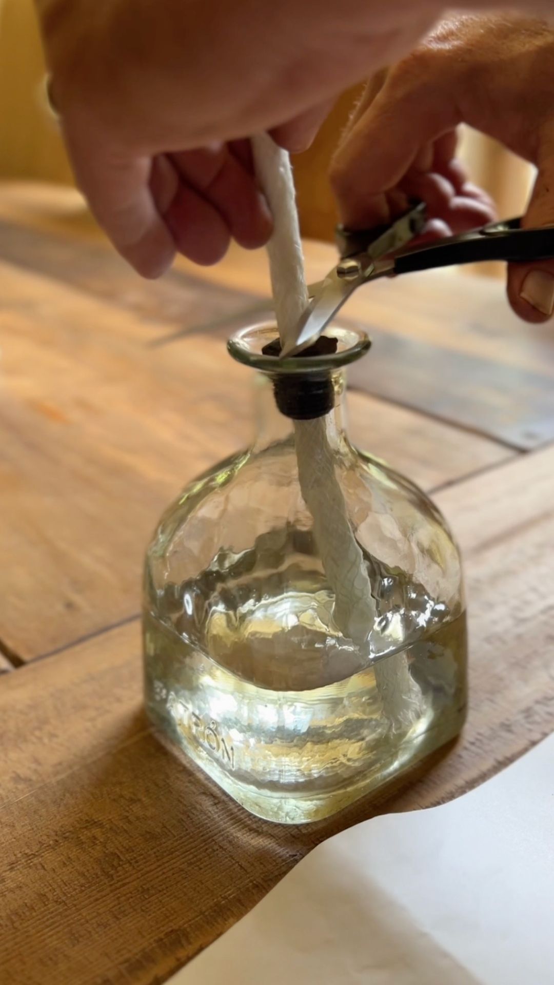 Glass bottle with a bushing with a wick being put into it. Filled with citronella.