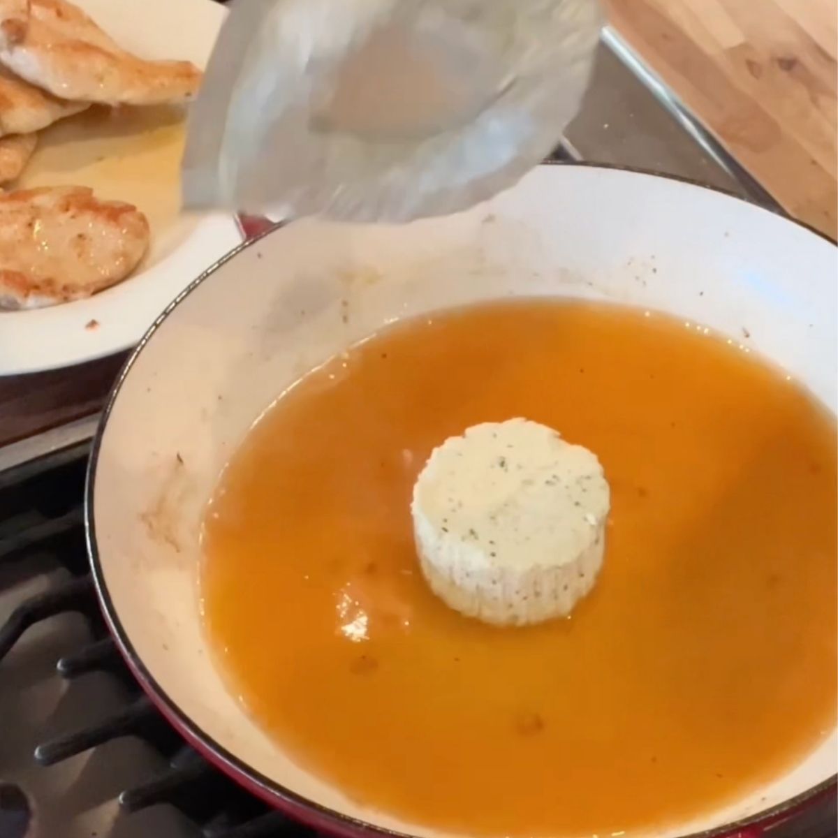 Boursin chicken is being added to the stock in a frying pan.