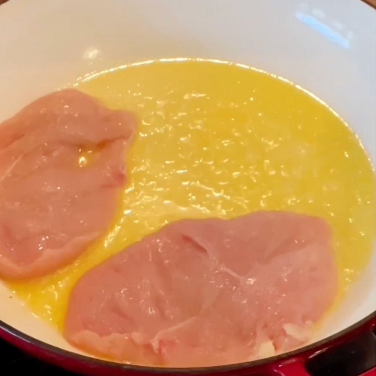 Chicken cutlets in a frying pan and olive oil.