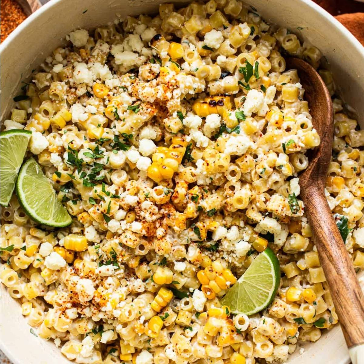 Elote pasta salad in a bowl with limes